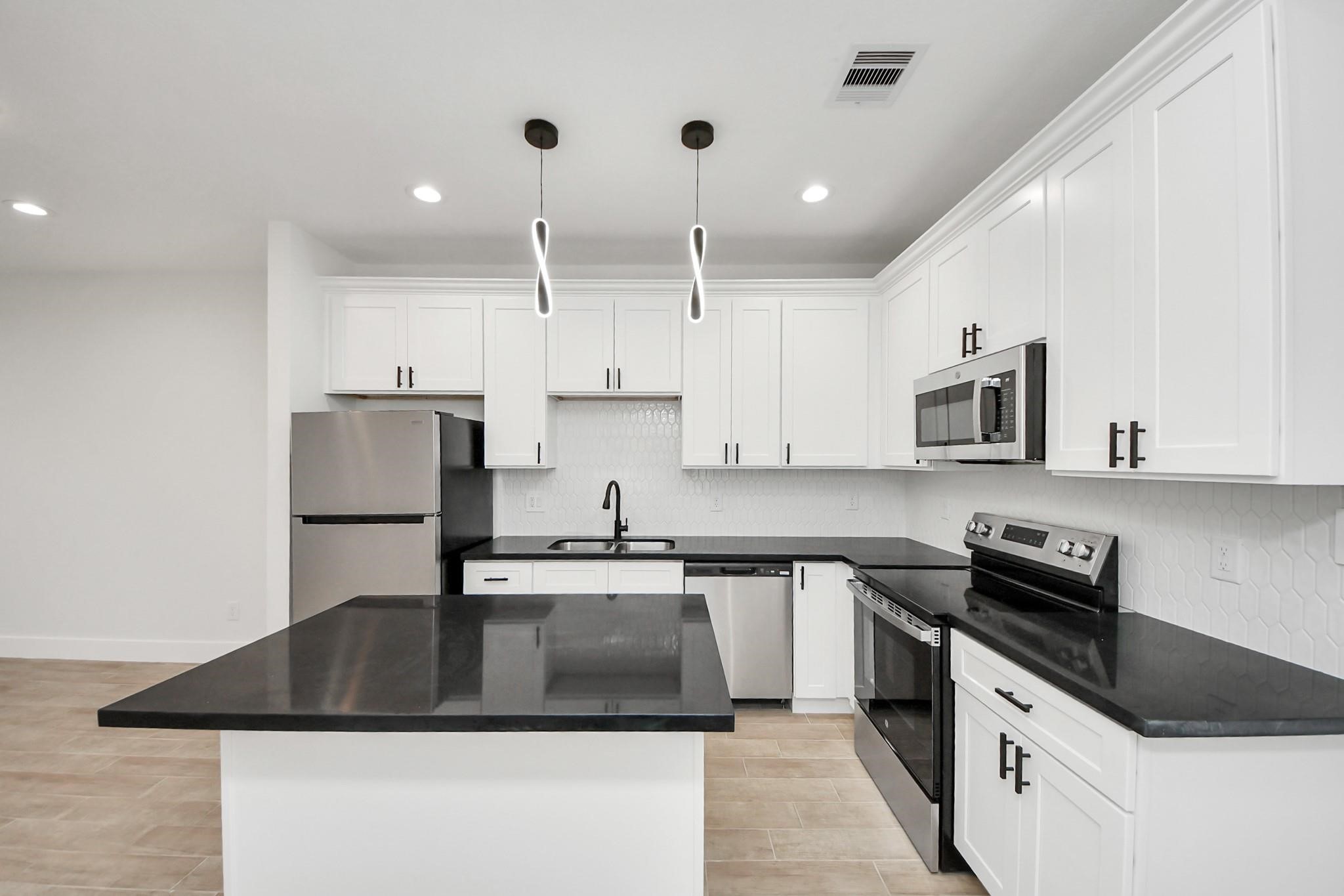 8015 Elbert Street, Unit A/B Houston, TX 77028 - Photo 5 of 12 a kitchen with kitchen island granite countertop a sink a stove and refrigerator