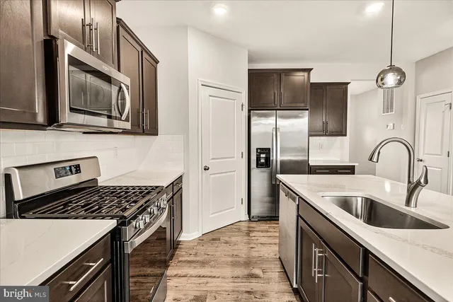 a kitchen with stainless steel appliances granite countertop a sink a stove a refrigerator cabinets and a kitchen island