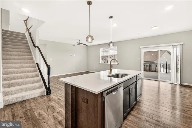 a kitchen with a sink a chandelier and wooden floor
