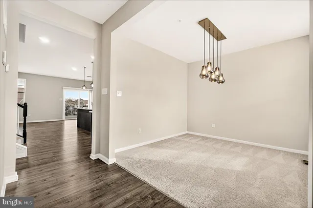 a view of a hallway with wooden floor and a bathroom