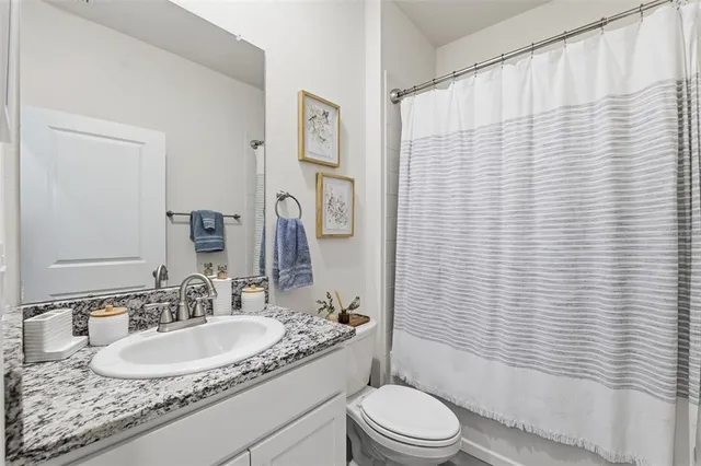 a bathroom with a granite countertop toilet sink and mirror
