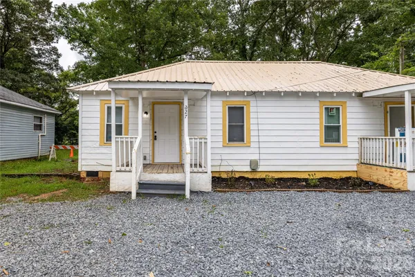 a view of a white house with a yard and table and chairs under an umbrella