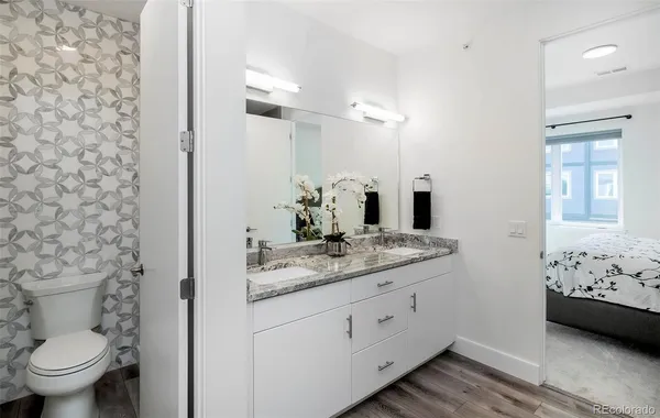 a bathroom with a granite countertop sink toilet and mirror
