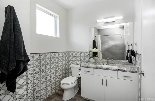 a bathroom with a granite countertop sink toilet and mirror