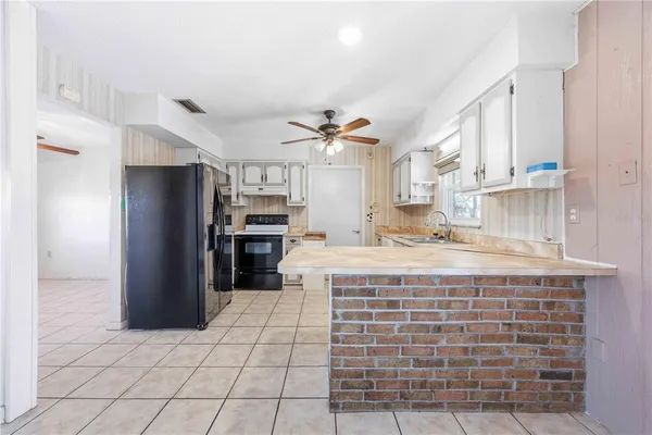 a large kitchen with stainless steel appliances kitchen island granite countertop a refrigerator and a sink