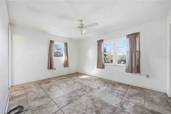 an empty room with windows and fan