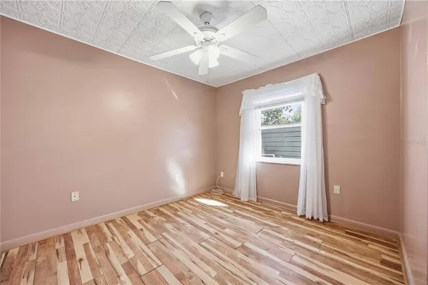an empty room with a window and a ceiling fan