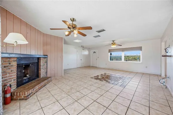 a view of an empty room and chandelier fan