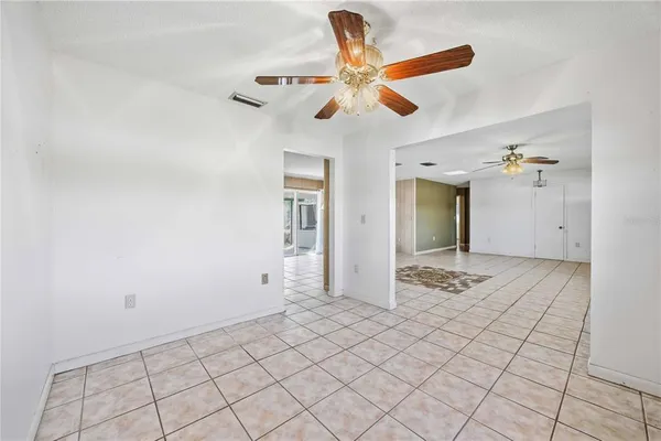 a view of a livingroom with a chandelier fan and kitchen view