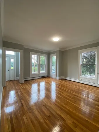 a view of empty room with window and wooden floor