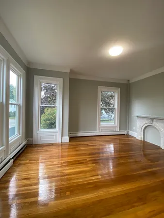a view of an empty room with window and wooden floor