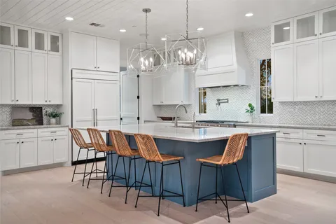 a kitchen with a dining table chairs sink and cabinets