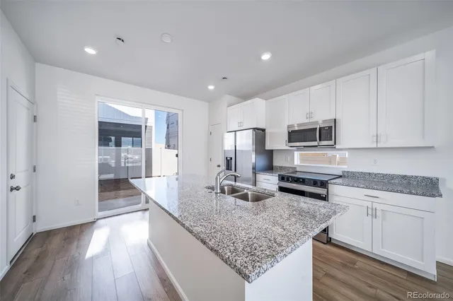 a kitchen with stainless steel appliances granite countertop a lot of counter space and wooden floors