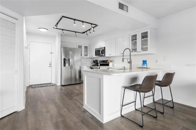 a kitchen with kitchen island white cabinets and stainless steel appliances