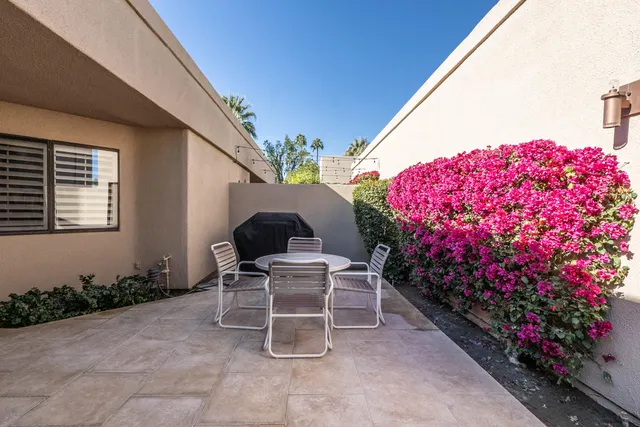 a patio with a table and chairs and potted plants