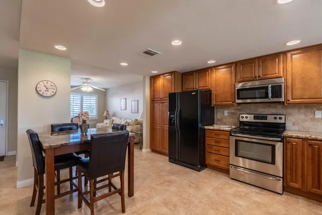 a kitchen with stainless steel appliances granite countertop a refrigerator a sink a stove a microwave and a refrigerator