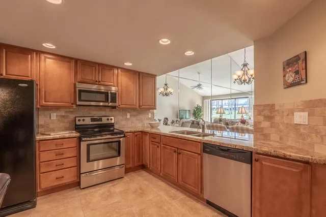 a kitchen with stainless steel appliances kitchen island granite countertop a refrigerator and cabinets