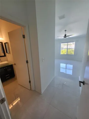 an empty room with windows and chandelier fan