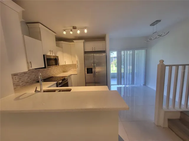 a kitchen with stainless steel appliances granite countertop a sink stove refrigerator and microwave