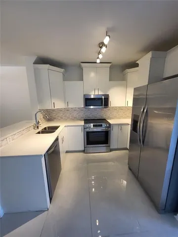 a kitchen that has a refrigerator a sink and cabinets