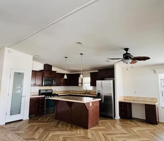 a large kitchen with stainless steel appliances kitchen island granite countertop a refrigerator and a stove top oven