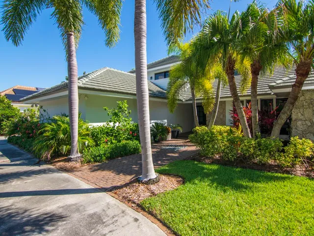 a view of a house with a yard and palm trees