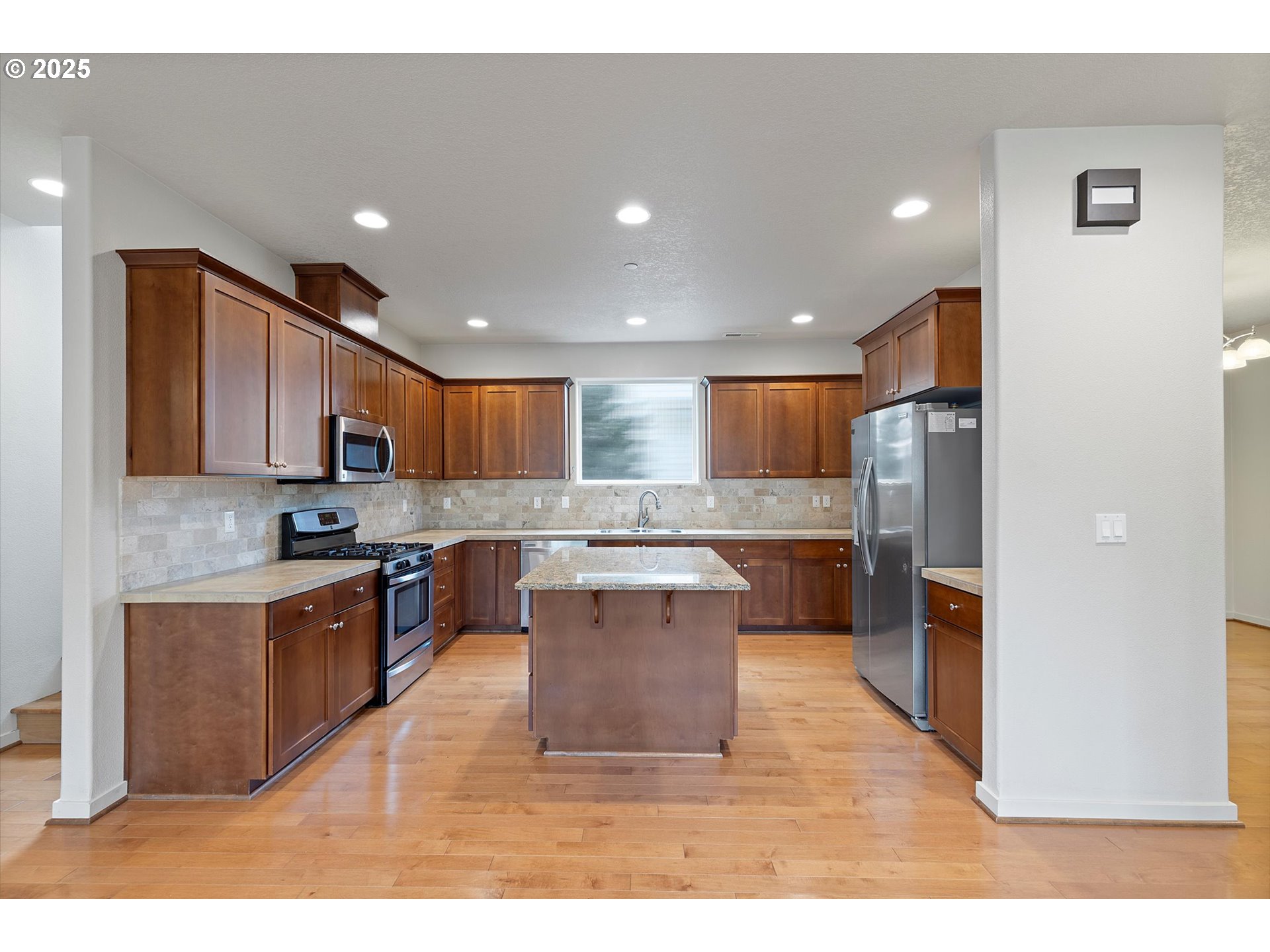 12001 Southwest Surrey Street Wilsonville, OR 97070 - Photo 11 of 48 a kitchen with stainless steel appliances kitchen island granite countertop a stove a sink a refrigerator and a refrigerator