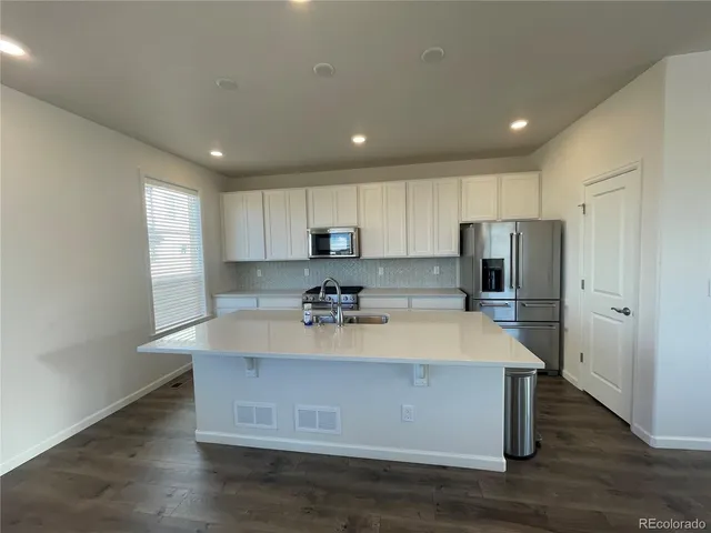 a view of a kitchen with kitchen island a sink wooden floor and a refrigerator