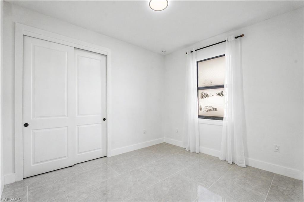 2239 Armour Road Lehigh Acres, FL 33973 - Photo 13 of 24 Bright interior space featuring light-toned tile flooring, clean white walls, and a window with white sheer curtains