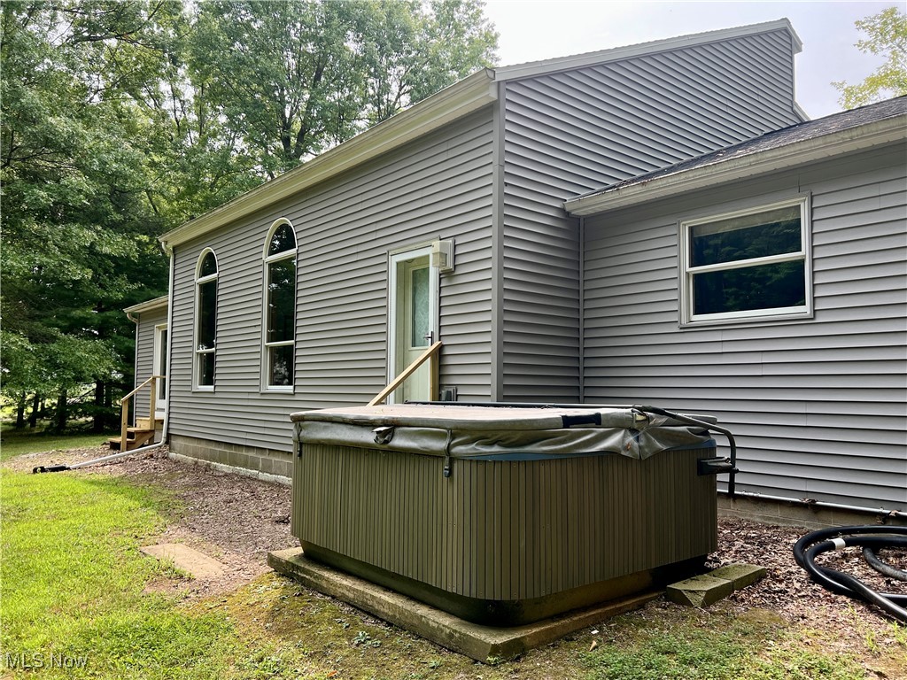Back of house featuring a hot tub