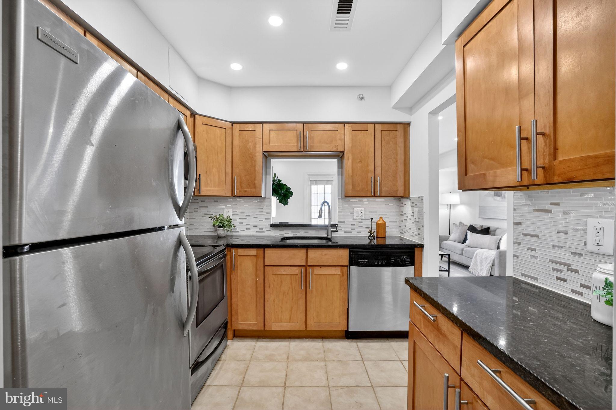 3805 Porter Street Northwest, Unit 201 Washington, DC 20016 - Photo 12 of 19 a kitchen with granite countertop stainless steel appliances a refrigerator a sink a stove cabinets and a counter top space