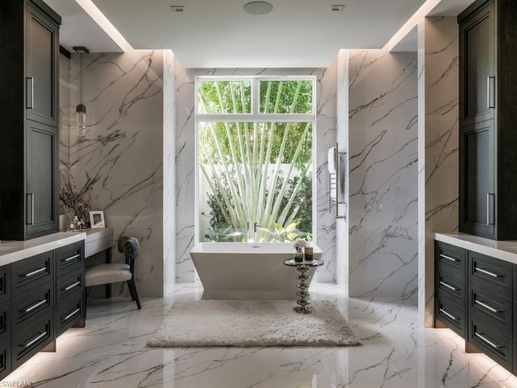 6199 Highcroft Drive Naples, FL 34119 - Photo 16 of 45 Primary Bathroom with floor to ceiling tiles, dual vanity, and a soaking tub