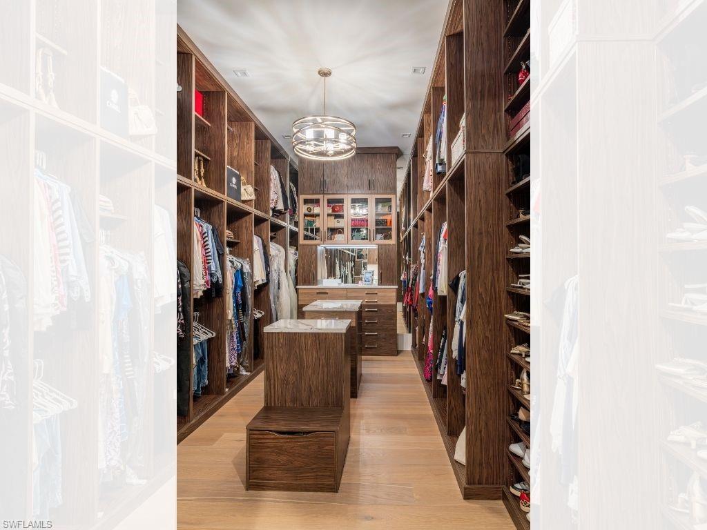 6199 Highcroft Drive Naples, FL 34119 - Photo 20 of 45 Primary walk in closet 1 with a chandelier and light wood-style flooring