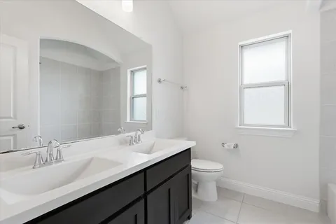 a bathroom with a double vanity sink toilet and a mirror