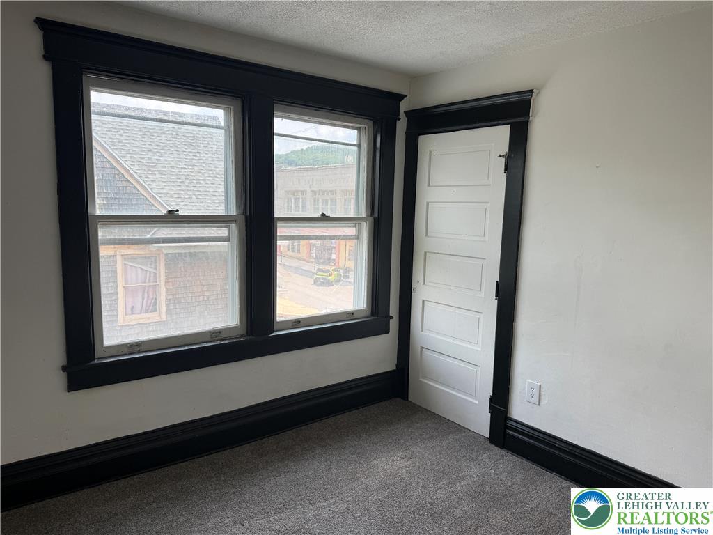 41 West Ridge Street Lansford, PA 18232 - Photo 30 of 40 Black trim accents the window and doorway in this room with a textured carpet.