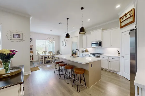 a kitchen with stainless steel appliances kitchen island granite countertop a stove a sink a dining table and chairs with wooden floor