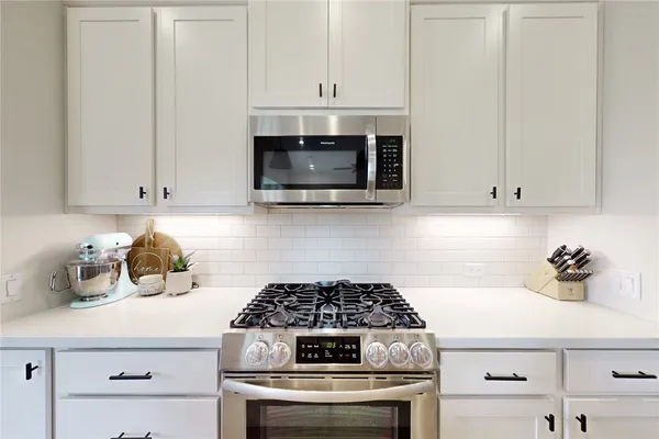 a kitchen with granite countertop white cabinets and white appliances