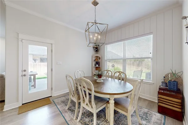 a dining room with wooden floor a chandelier a glass table and chairs