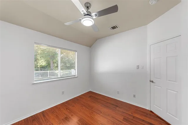 a view of an empty room with window and wooden floor