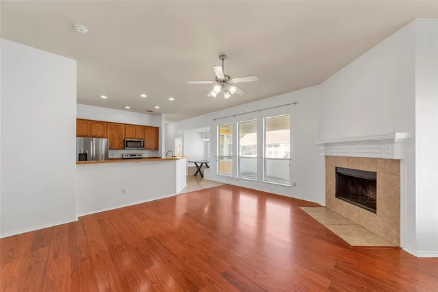 a view of an empty room with wooden floor and a fireplace