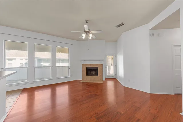 an empty room with wooden floor fireplace and windows
