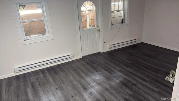 an empty room with wooden floor cabinet and windows
