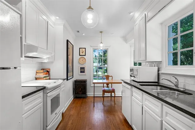 a kitchen with granite countertop a sink appliances cabinets and furniture