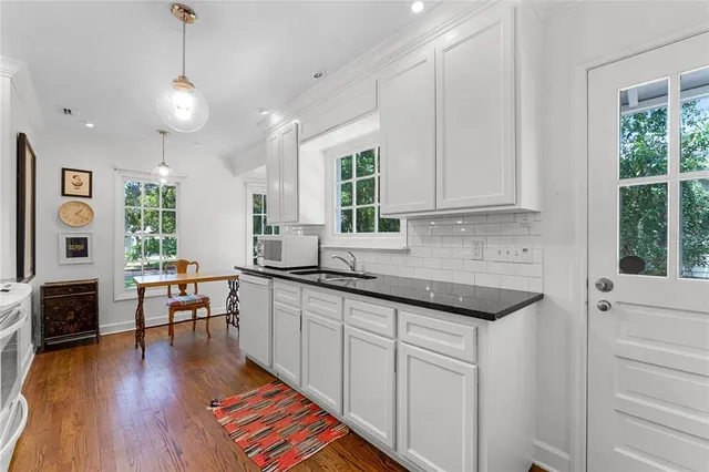 a kitchen with stainless steel appliances granite countertop a stove a sink dishwasher and a microwave with wooden floor