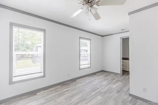a view of an empty room with a window and wooden floor