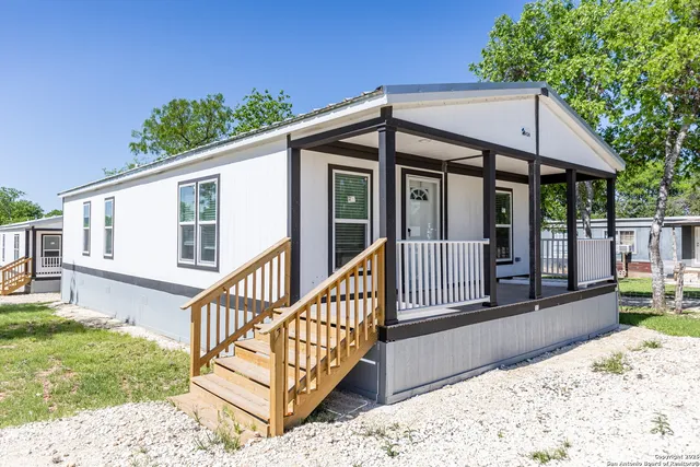 a view of a house with a small yard and wooden deck