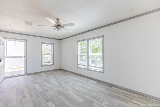a view of empty room with wooden floor and fan