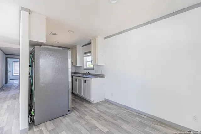 a view of a kitchen with refrigerator and white cabinets