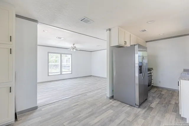a view of a kitchen with a refrigerator and wooden floor