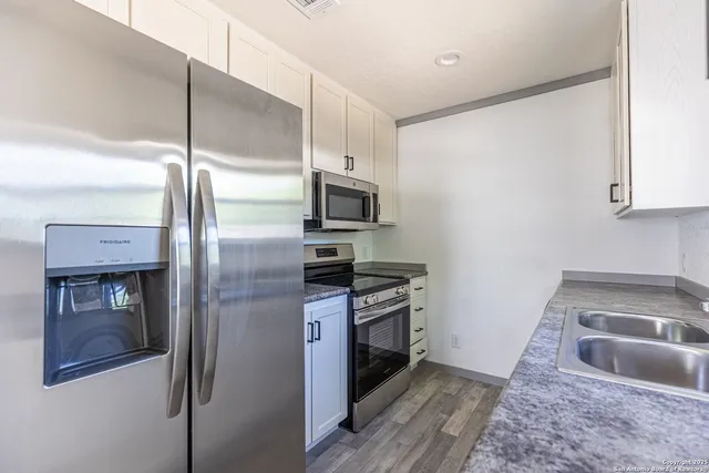 a kitchen with stainless steel appliances granite countertop a refrigerator and a sink